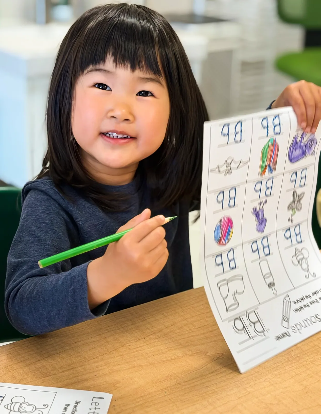 A Starbright student proudly holding up her completed letter worksheet