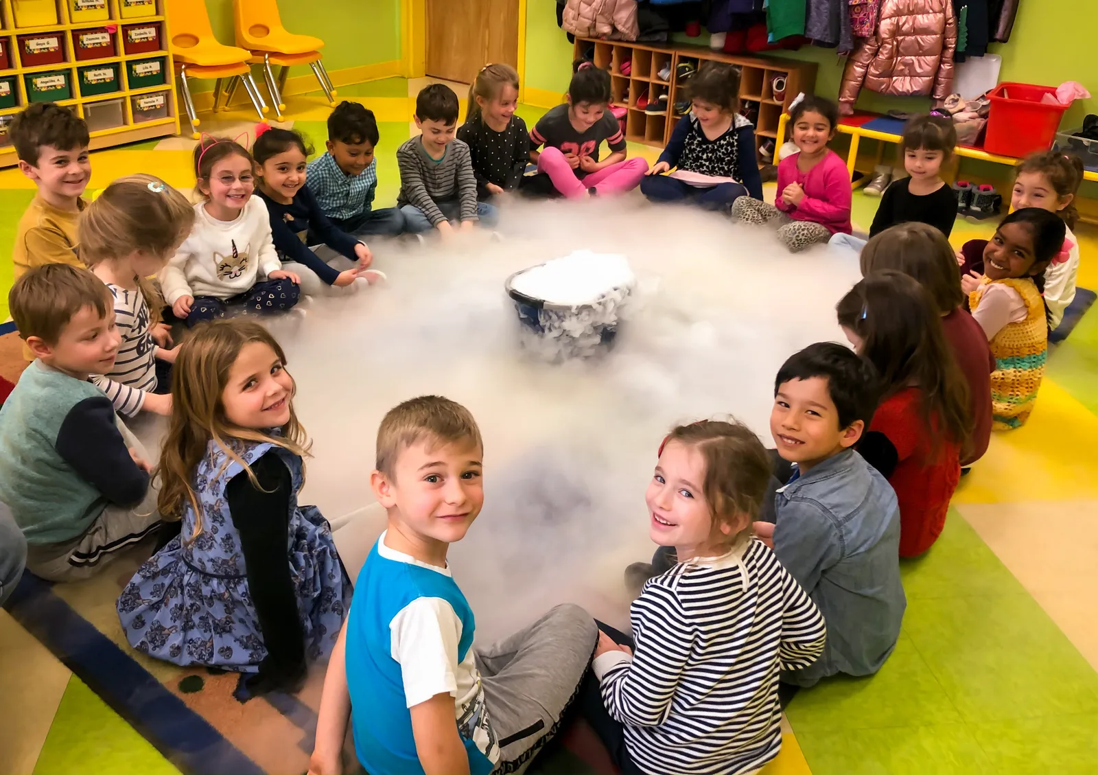 Starbright students gathered around a classroom science experiment sending up a cloud of vapor