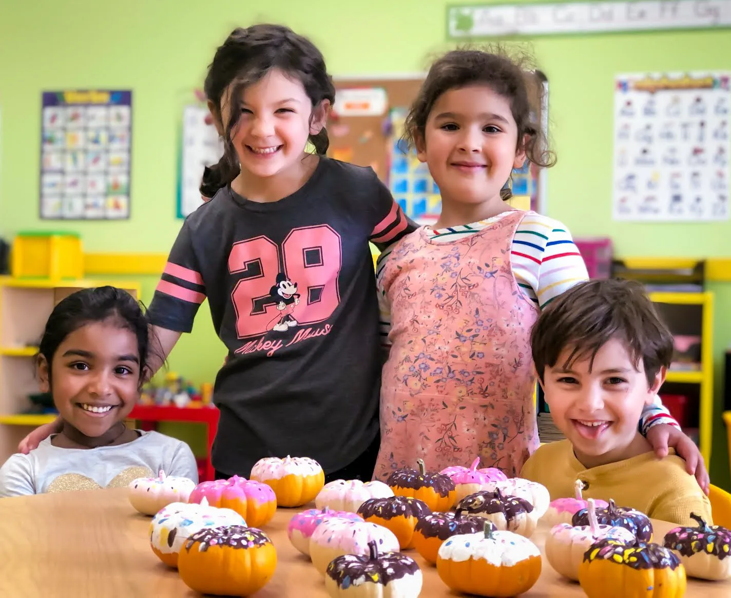 Starbright Kindergarten students standing behind a table of pumpkins they decorated