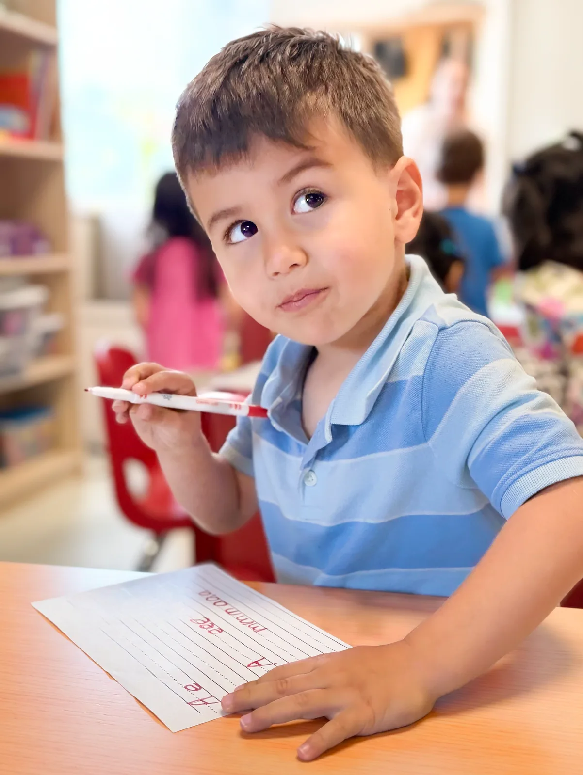 A Starbright preschooler writing his name with a red marker