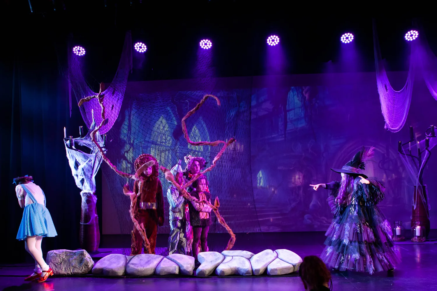 Starbright students performing a dramatic forest scene under purple lights